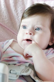Baby-girl with finger in mouth watching something interesting