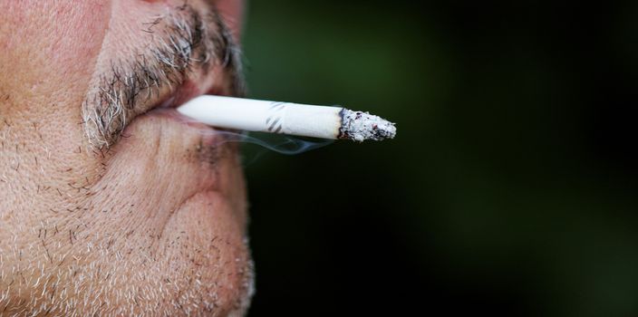 Smoking a cigarette against a dark background