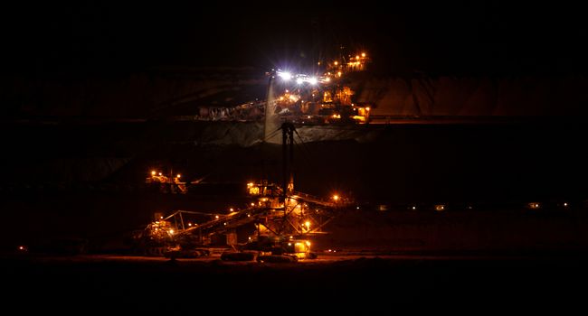 Coal mining in an open pit with huge industrial machine at night shoot