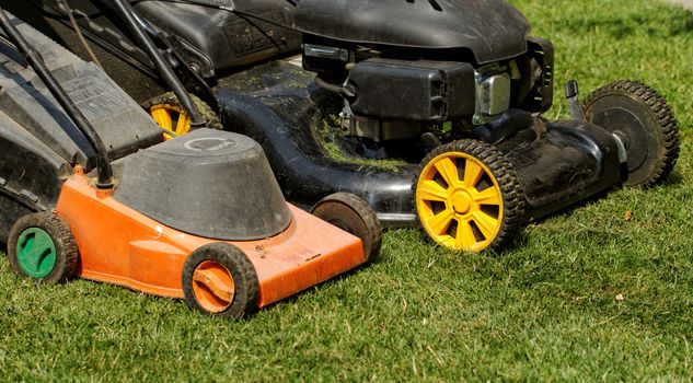 two lawnmower in the garden lawn the grass (fuel and electricity)