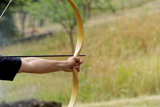 archery man shooting arrow with bow in the nature