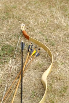 color archery arrows and bow in nature on the ground