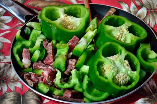 Raw beef slices and green pepper pieces make for the ingredients for pepper steak