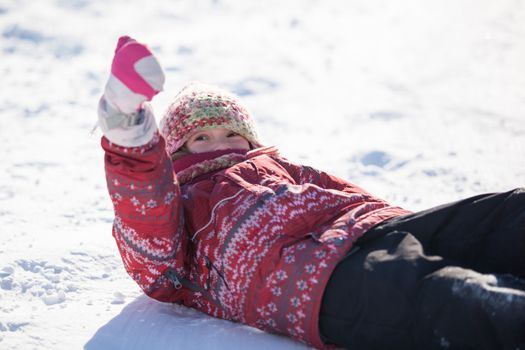 girl laying in the snow with her thumb up
