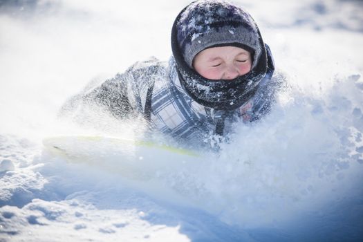 Boy taking a jump while sliding in the snow