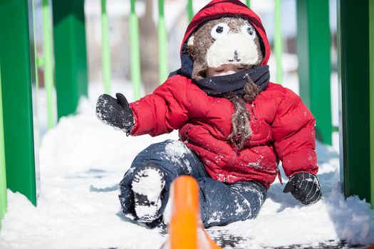 Infant playing on a slider in the snow