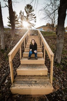 Woman sitting on a wooden staircase outside