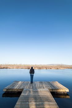 Woman standing on a wooden deck besides a lake