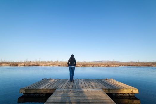 Woman standing on a wooden deck besides a lake