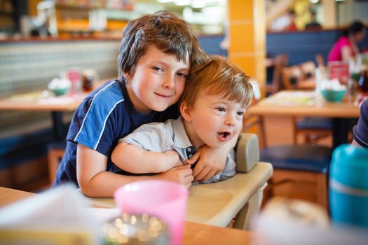 Brothers hugging while waiting in a restaurant