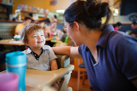 Boy playing with his mther while sitting in a restaurant