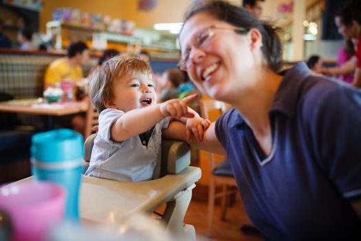 Boy playing with his mther while sitting in a restaurant