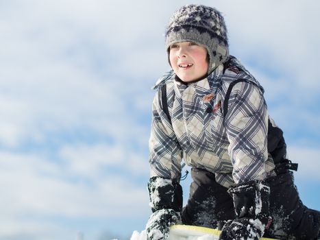 Boy playing in the snow and sliding on a board