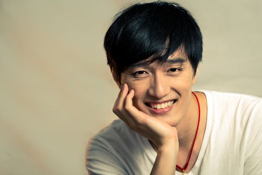 Young man supporting chin and smiling, with fashion tone and background