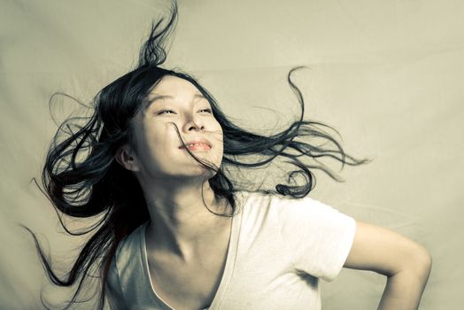 Young woman flicking her hair and posing, with fashion tone and background