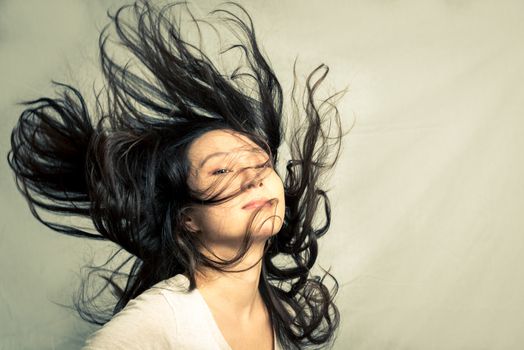 Young woman flicking her hair and posing, with fashion tone and background