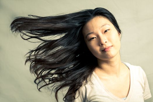 Young woman flicking her hair and posing, with fashion tone and background