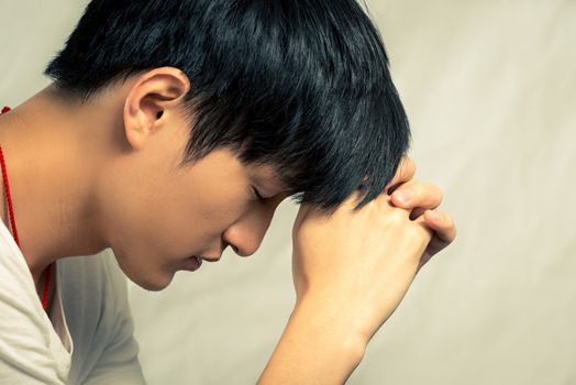 Young man supporting his head looking depressed, in fashion tone and background