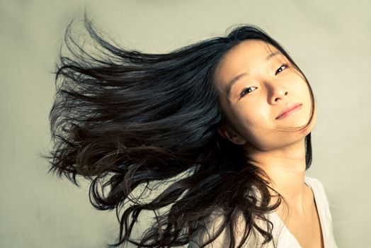 Young woman flicking her hair and posing, with fashion tone and background