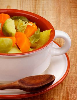 Homemade Rustic Vegetable Stew with Carrot, Broccoli, Potato and Leek in Bowl with Wooden Spoon on Wooden background