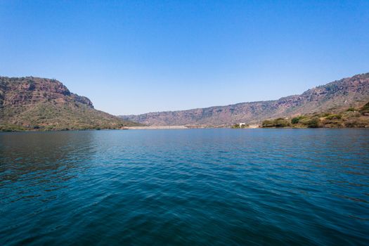 River waters blue sky with distant Dam wall in valley neck