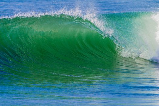 Clean ocean wave breaking crashing onto shallows