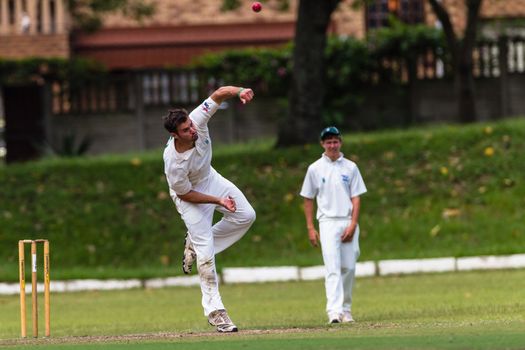 Spin bowler flights ball to batsman with fielders alert for runs in a local match league fixture.