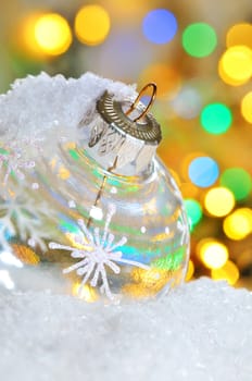 Transparent Christmas ball on snowy winter and yellow lights