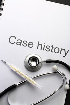 Case history, stethoscope and thermometer on black