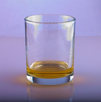 Glass with a little whisky over grey white background