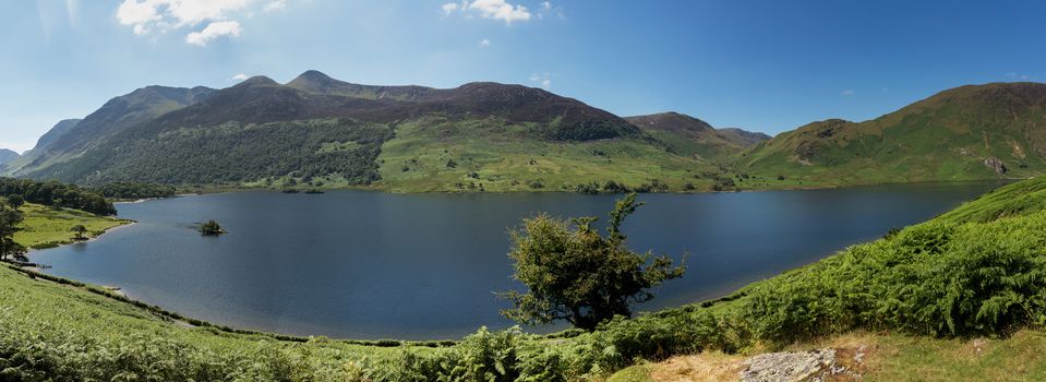 Panorama of the Lake District hills surrounding Crummock Water framed by the trees on the lakeside. Idyllic image from the English Lakes