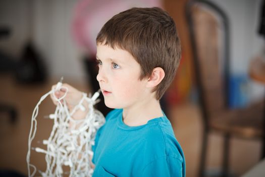 Boy holding lights to decorate the Christmas tree