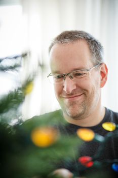 Man decorating a Christmas Tree inside a house