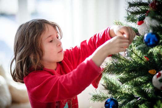 Girl decorating a Christmas tree inside a house