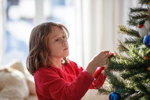 Girl decorating a Christmas tree inside a house