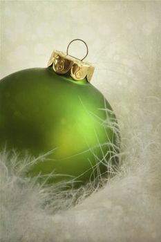 Green christmas ball on soft white feathers