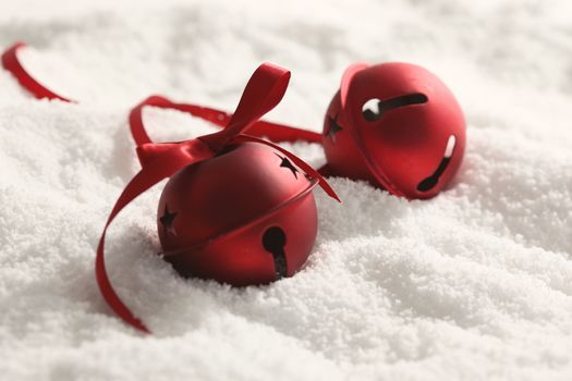 Red Christmas bells with ribbon in snow