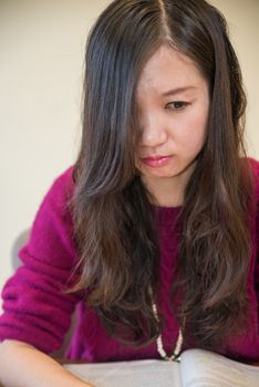 Sad young woman looking depressed with open book