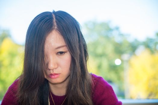 Sad looking young woman in front of a large window