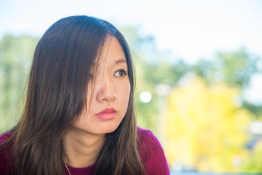 Sad looking young woman in front of a large window