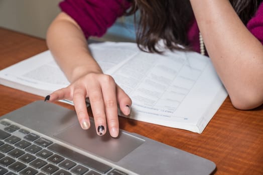 Hands working on a laptop with various desk objects