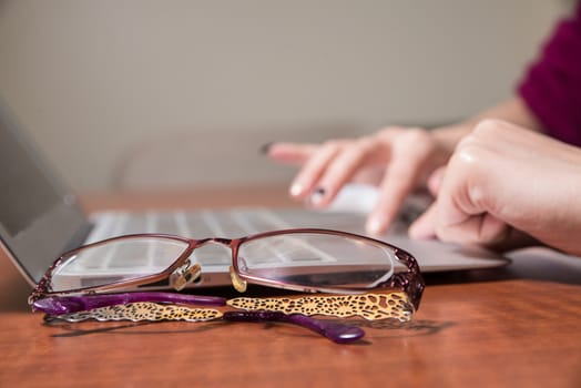 Hands working on a laptop with various desk objects