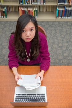 Woman with book and laptob studying in library