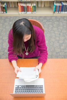 Woman with book and laptob studying in library