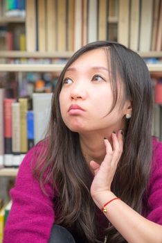 Portrait of young woman in front of book shelf