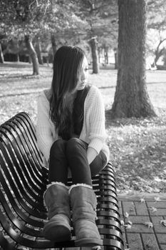 lonely young woman sitting on a steel bench