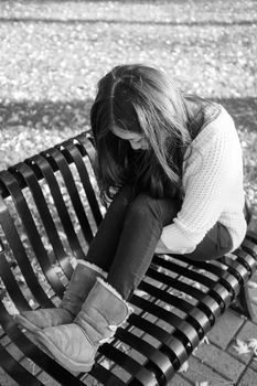 lonely young woman sitting on a steel bench