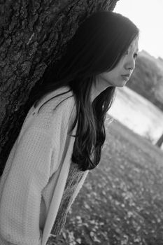 Woman standing next to a tree looking depressed