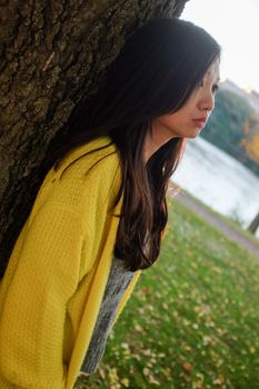 Woman standing next to a tree looking depressed