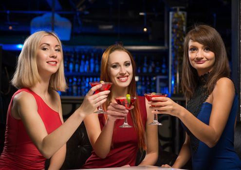 three girls raised their glasses in a nightclub, have fun with friends